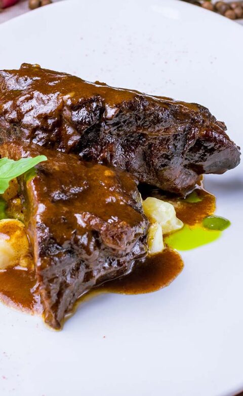 Roast beef plated on top of mashed potatoes