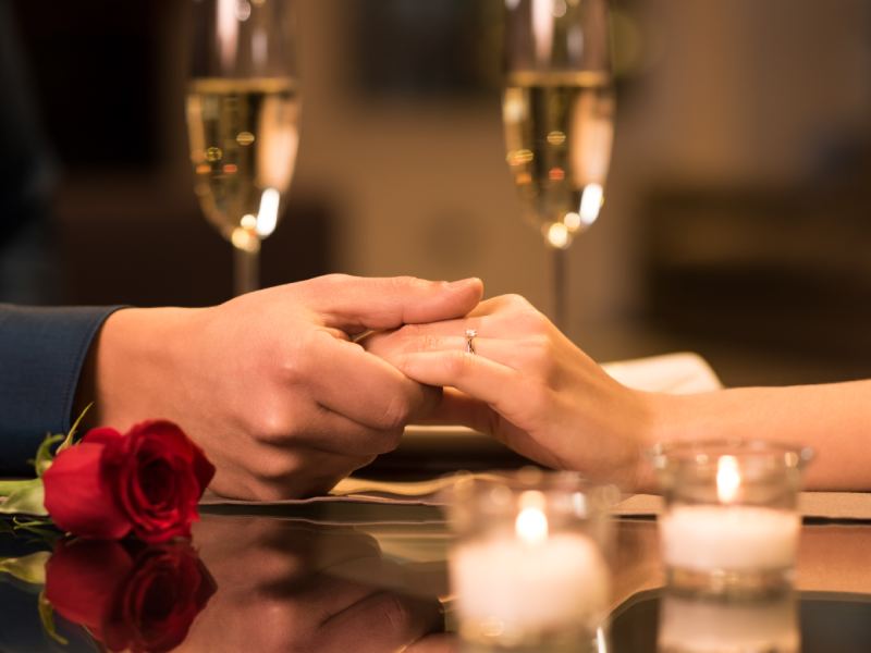 Couple holding hand at Valentine day with 2 wine glass at background