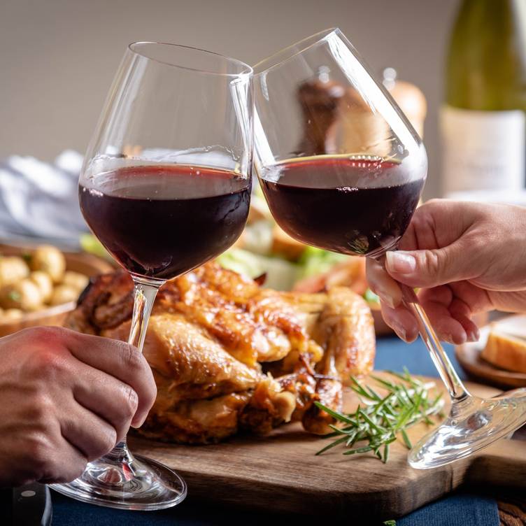 2 Hand with Wine glass and grilled chicken at background.