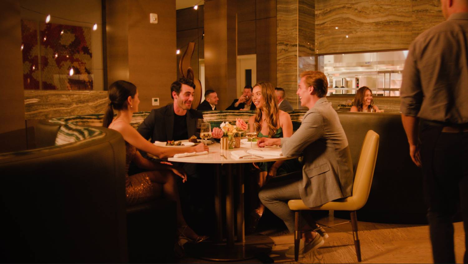 Group of friends enjoying dinner and conversation together at an upscale restaurant.