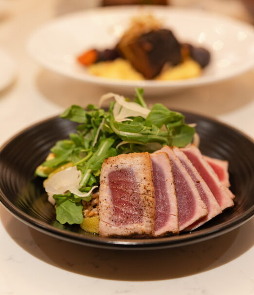 Seared tuna slices served with fresh greens in a bowl