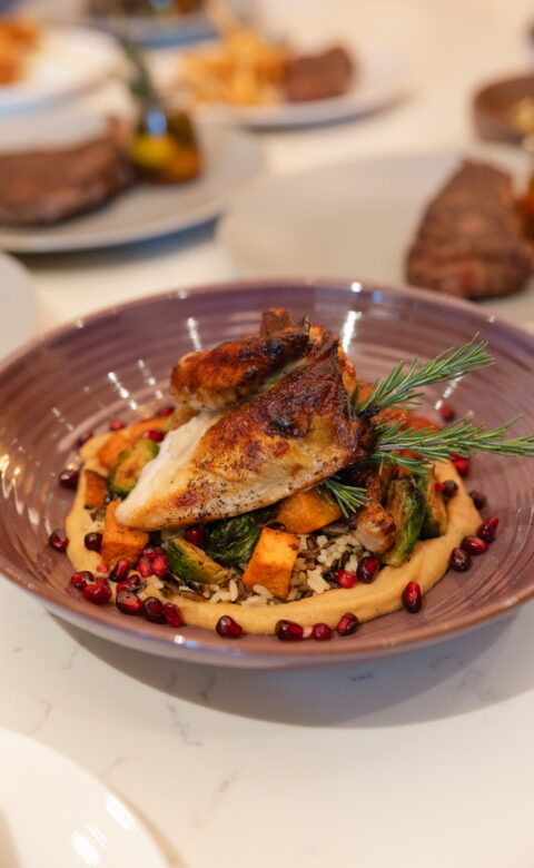 Roasted chicken breast over grains with vegetables and pomegranate seeds